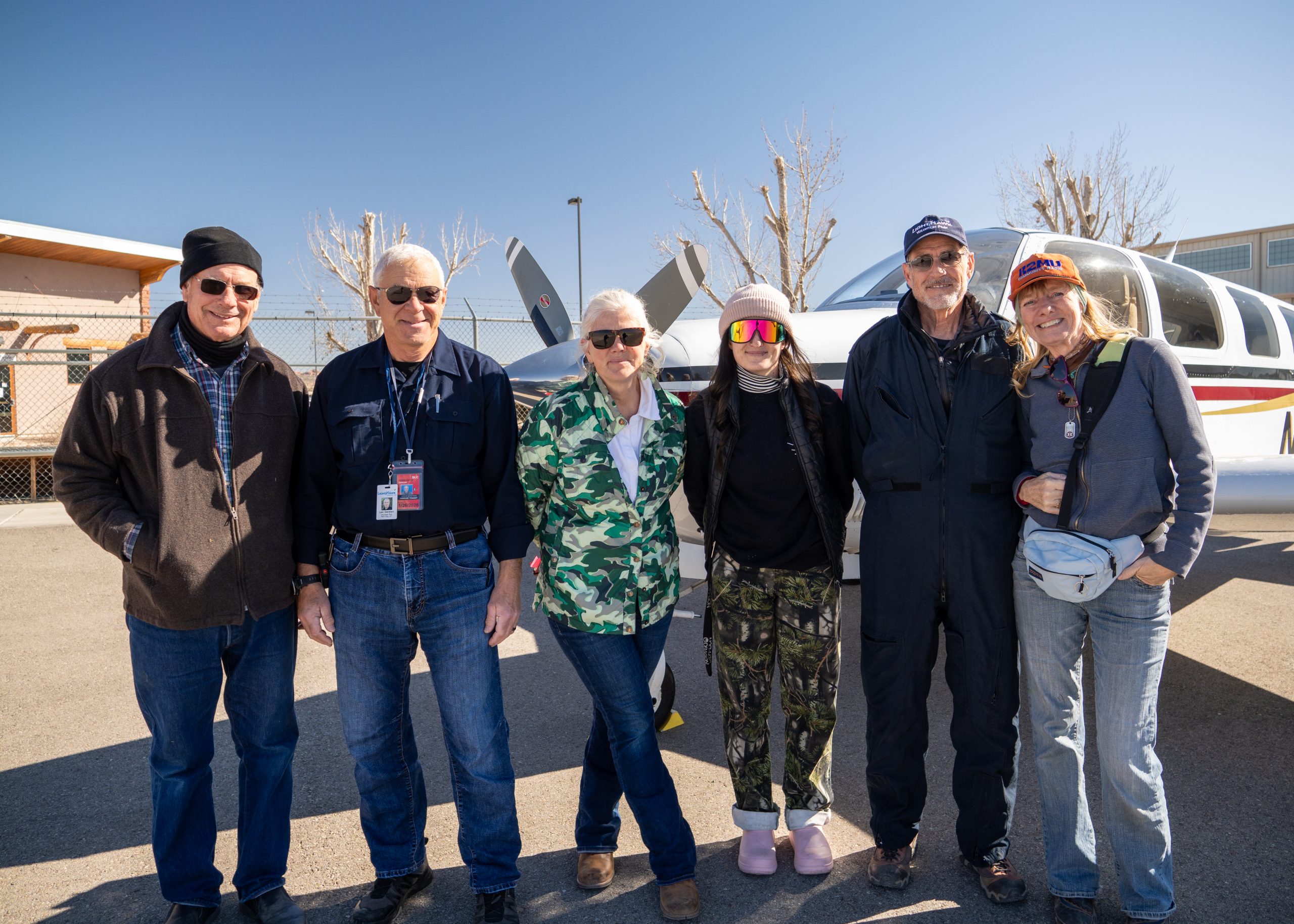 Group of six people standing in front of a small aircraft.