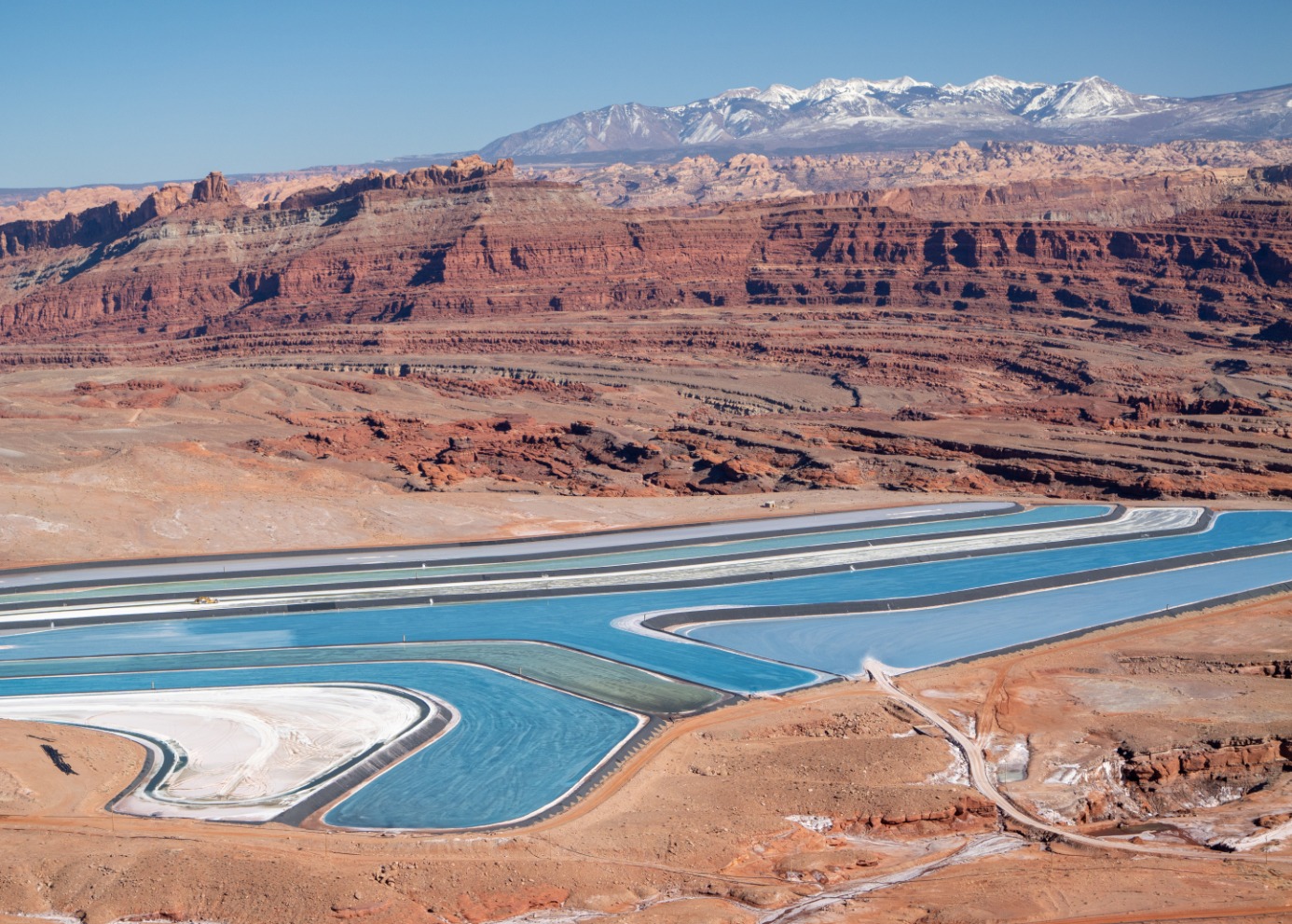 Mining evaporation ponds in front of beautiful red rock landscapes.